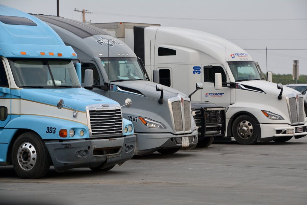 A row of parked semi trucks in Eagle Pass, Texas, showcasing various models and colors.